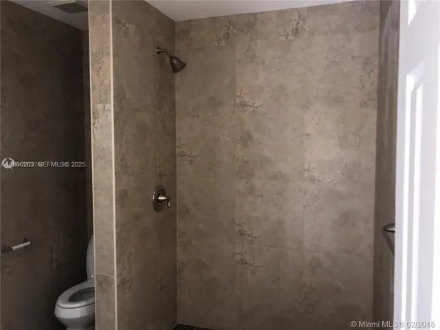 a bathroom with a granite countertop toilet and a shower