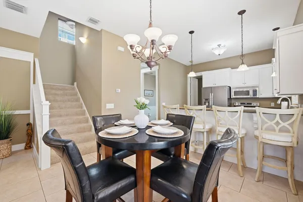 a kitchen with stainless steel appliances granite countertop a dining table chairs and a refrigerator
