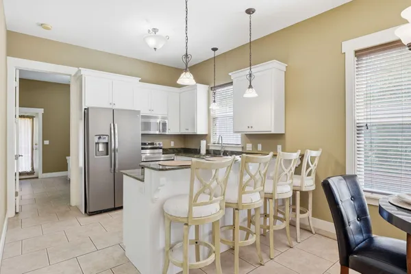 a kitchen with granite countertop white cabinets white stainless steel appliances a sink and a window