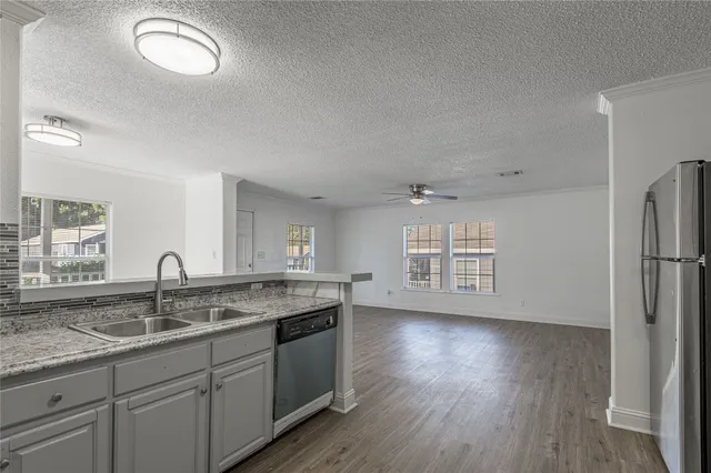 a kitchen with granite countertop a sink cabinets and wooden floor