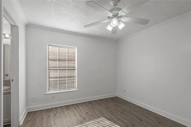 an empty room with wooden floor chandelier fan and windows