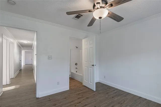 an empty room with wooden floor fan and windows