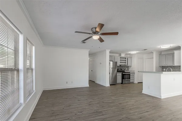 a view of a kitchen with a refrigerator a ceiling fan and wooden floor