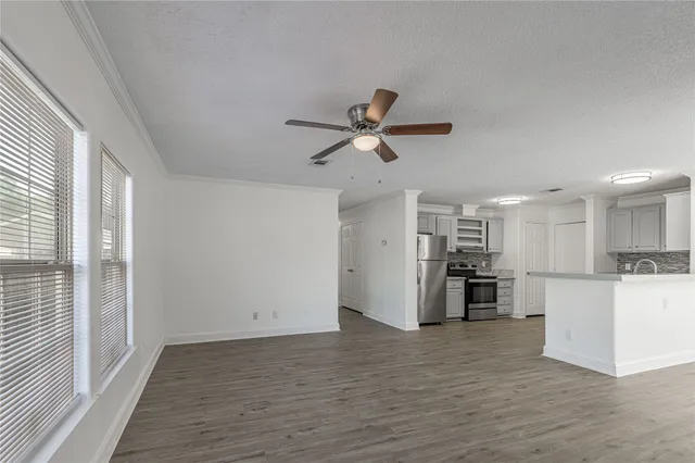 a view of a kitchen with a refrigerator a ceiling fan and wooden floor