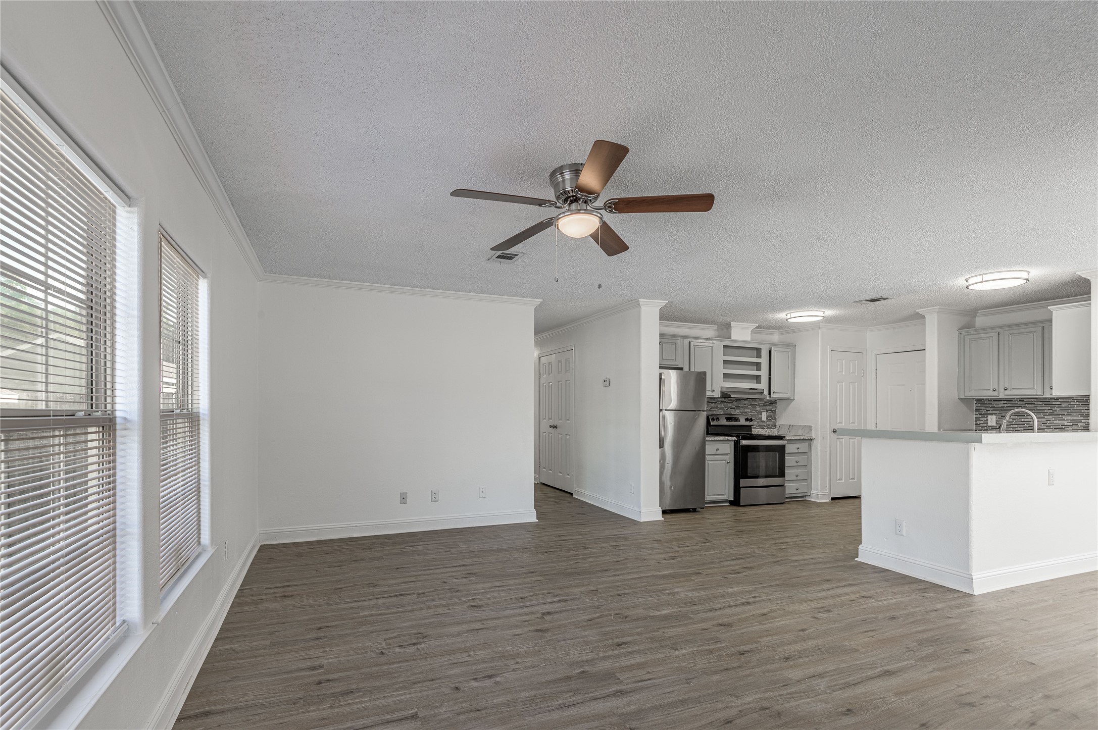 121 Varsity Circle Huntsville, TX 77340 - Photo 5 of 32 a view of a kitchen with a refrigerator a ceiling fan and wooden floor