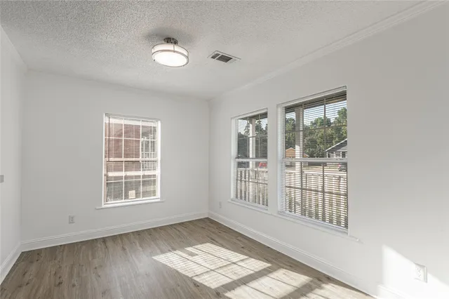 an empty room with wooden floor and windows
