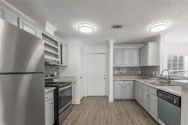 a kitchen with stainless steel appliances a refrigerator a sink and white cabinets