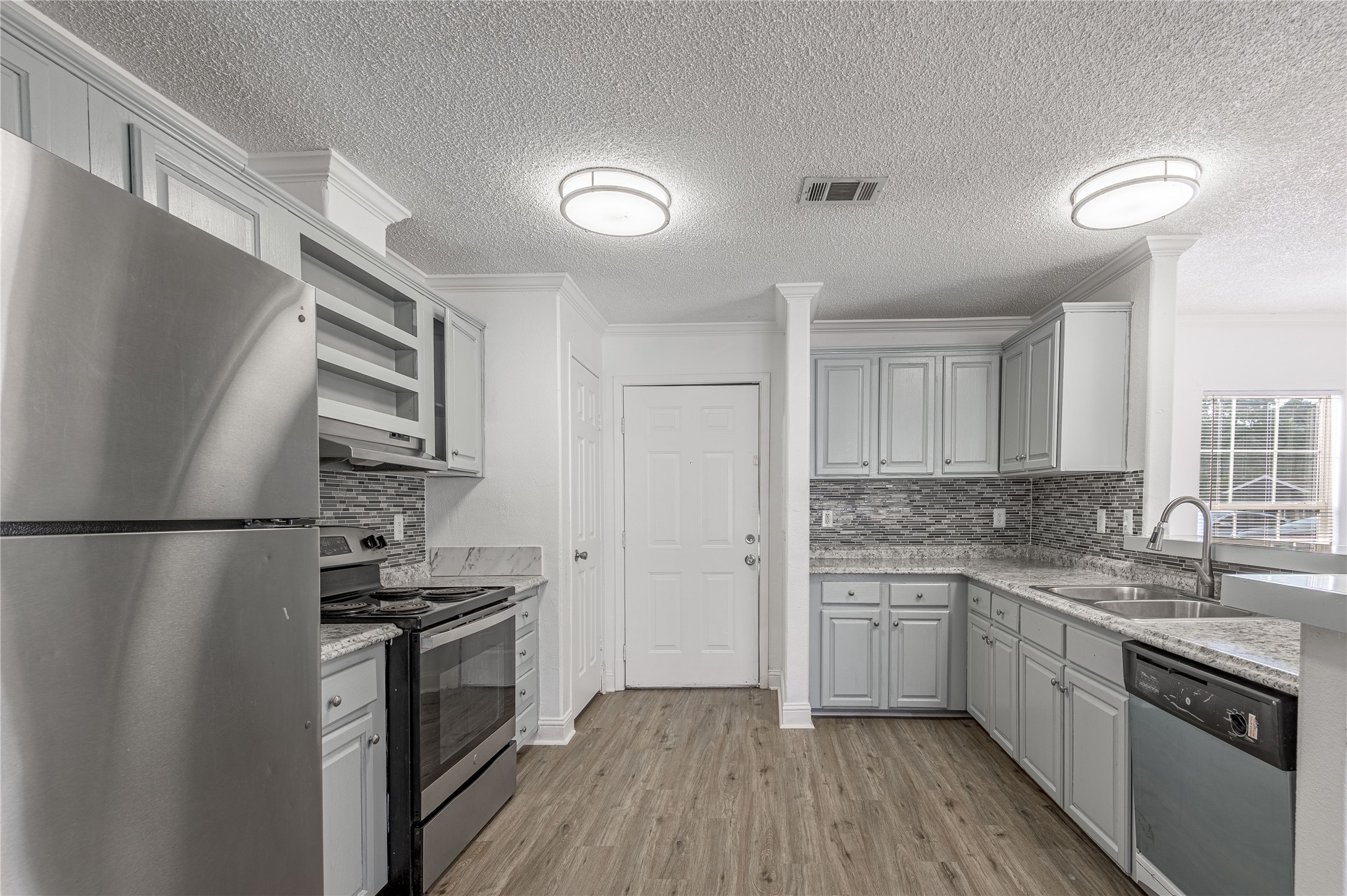 121 Varsity Circle Huntsville, TX 77340 - Photo 10 of 32 a kitchen with stainless steel appliances a refrigerator a sink and white cabinets