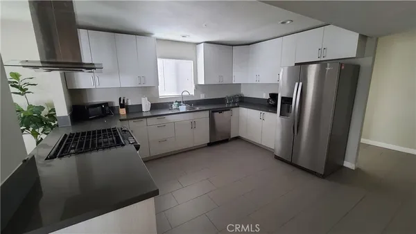 a kitchen with a refrigerator sink and white cabinets