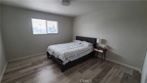 a bedroom with a bed window and wooden floor