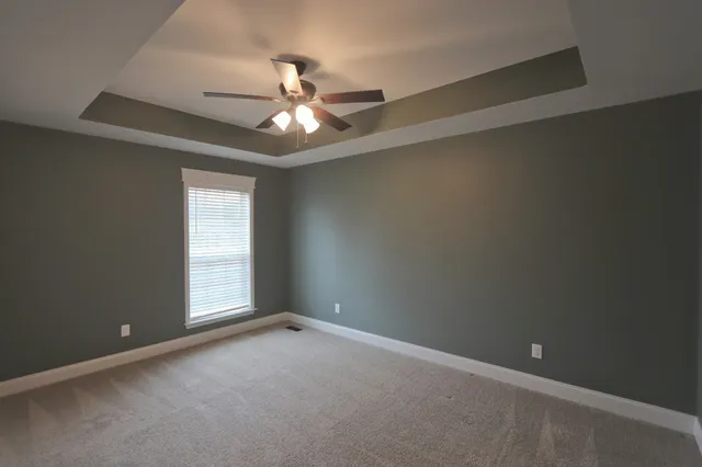 an empty room with a window and ceiling fan