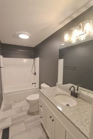 a bathroom with a granite countertop sink a toilet and shower
