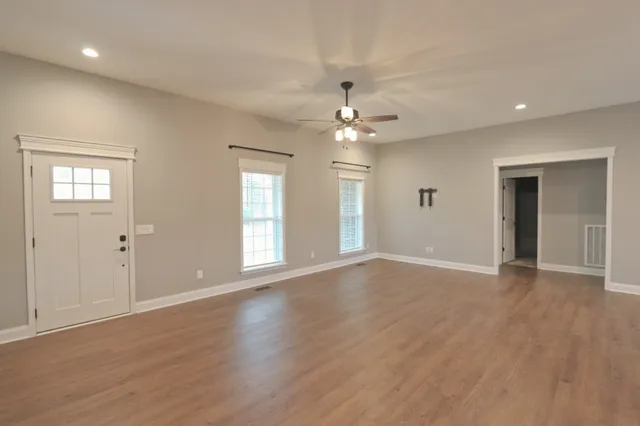 a view of an empty room with window and wooden floor