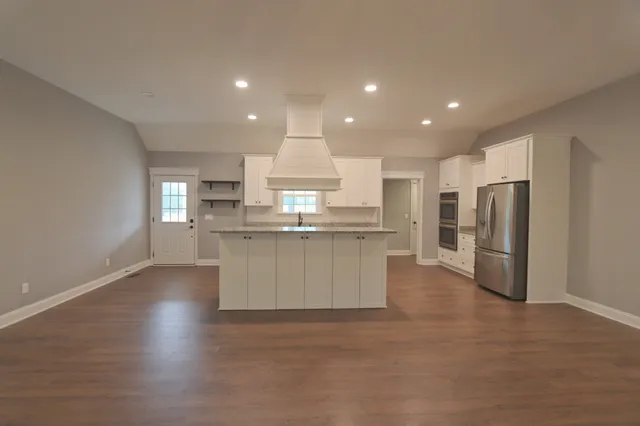 a kitchen with stainless steel appliances kitchen island hardwood floor sink stove refrigerator and cabinets