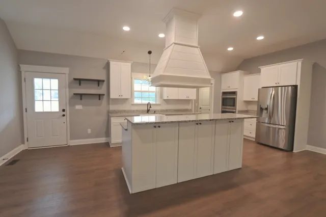 a kitchen with stainless steel appliances granite countertop a refrigerator a sink dishwasher a stove and a refrigerator with wooden floor