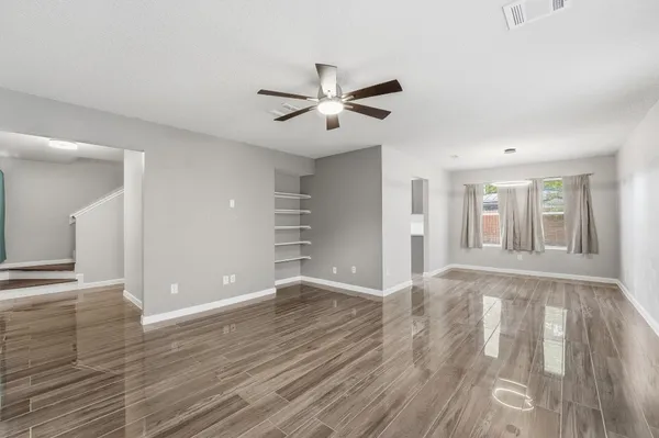 a view of an empty room with window and wooden floor