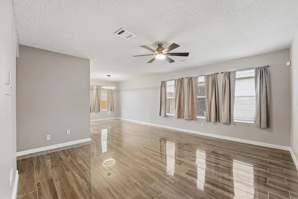 a view of an empty room with a window and wooden floor