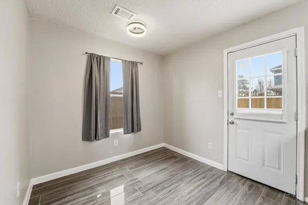 an empty room with wooden floor and windows