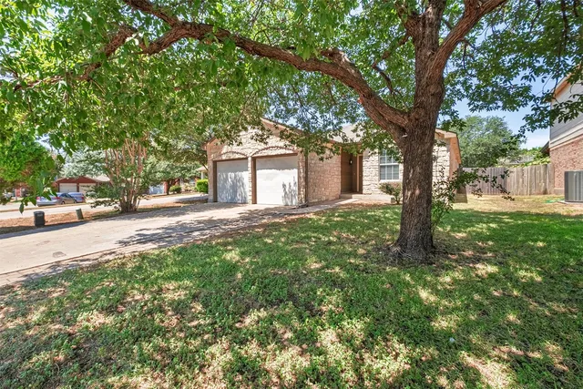 a front view of a house with a yard and large trees