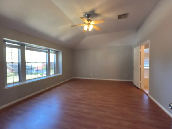 an empty room with wooden floor and windows