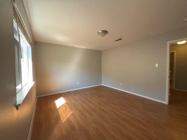 an empty room with wooden floor and windows