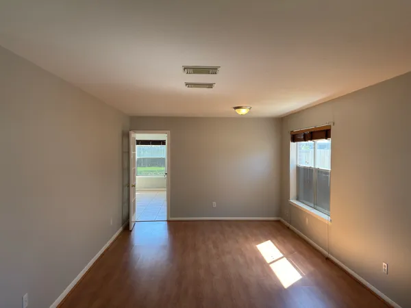 an empty room with wooden floor and windows
