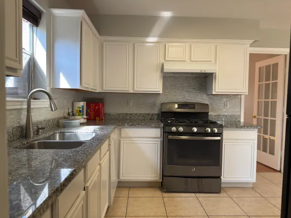 a kitchen with granite countertop a sink stove and cabinets