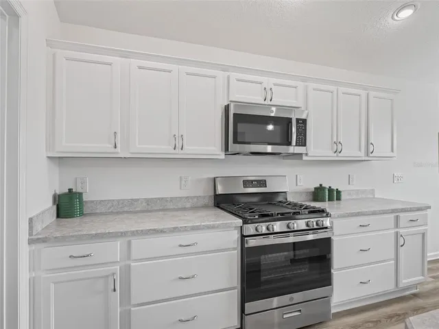 a kitchen with granite countertop white cabinets and stainless steel appliances