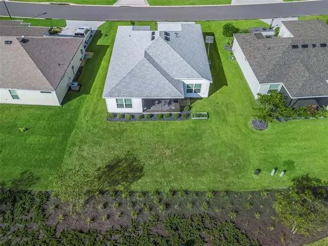 an aerial view of residential houses with outdoor space and trees