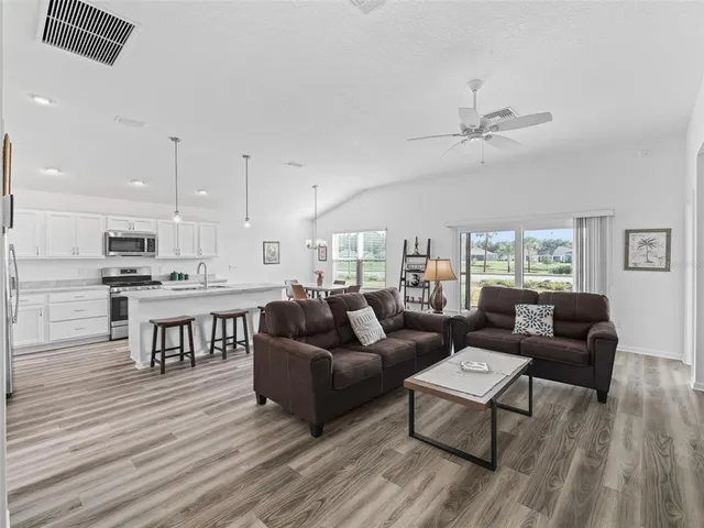 a living room with furniture kitchen view and a wooden floor