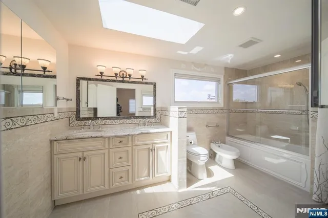 a bathroom with a granite countertop sink a toilet a mirror and shower