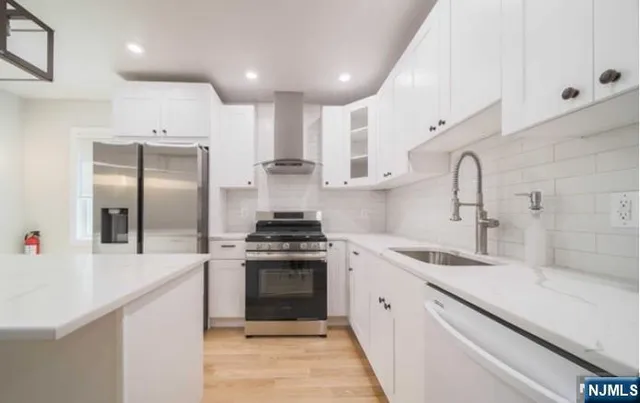 a kitchen with stainless steel appliances granite countertop a sink a stove and a refrigerator