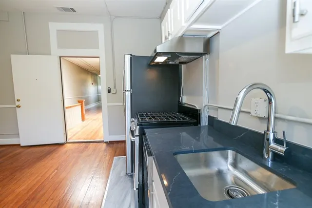 a kitchen with a sink a refrigerator and wooden floor