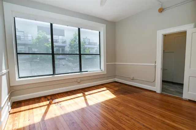 a view of an empty room with wooden floor and a window