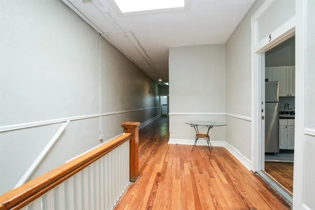 a hallway with wooden floor table and chairs