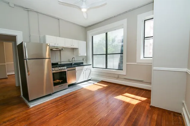 a kitchen with granite countertop a refrigerator and wooden floor