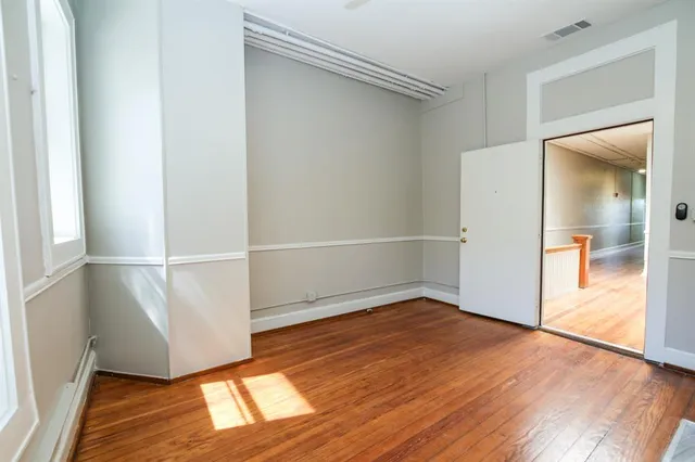 an empty room with wooden floor and entrance