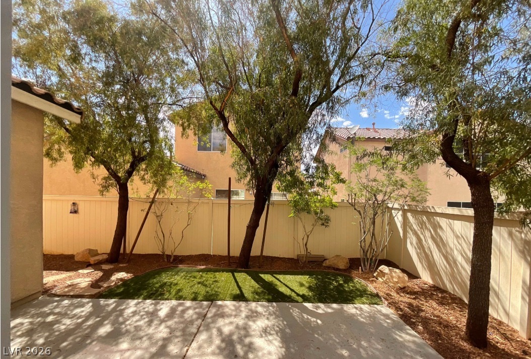 10841 Paradise Road Henderson, NV 89052 - Photo 35 of 35 A well-maintained private yard with mature trees and artificial turf offers a tranquil outdoor retreat.