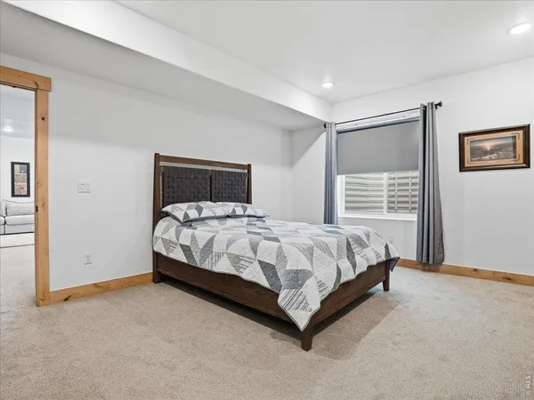 a bed sitting in a spacious bedroom next to a window and wooden floor