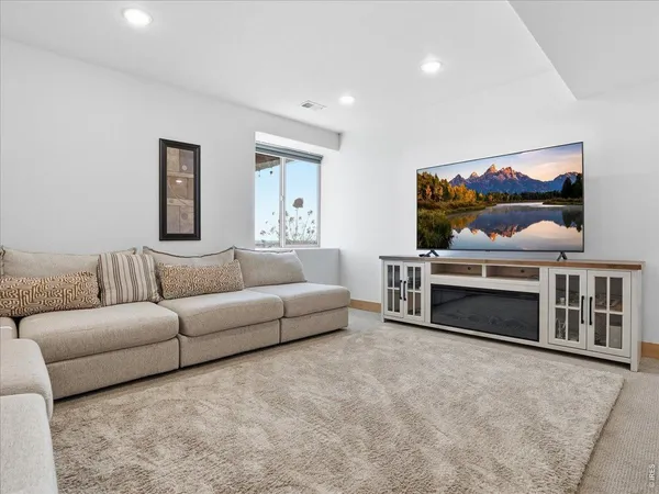 a living room with furniture a flat screen tv and kitchen view