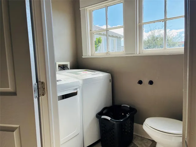 a bathroom with a granite countertop toilet a sink a window and a shower