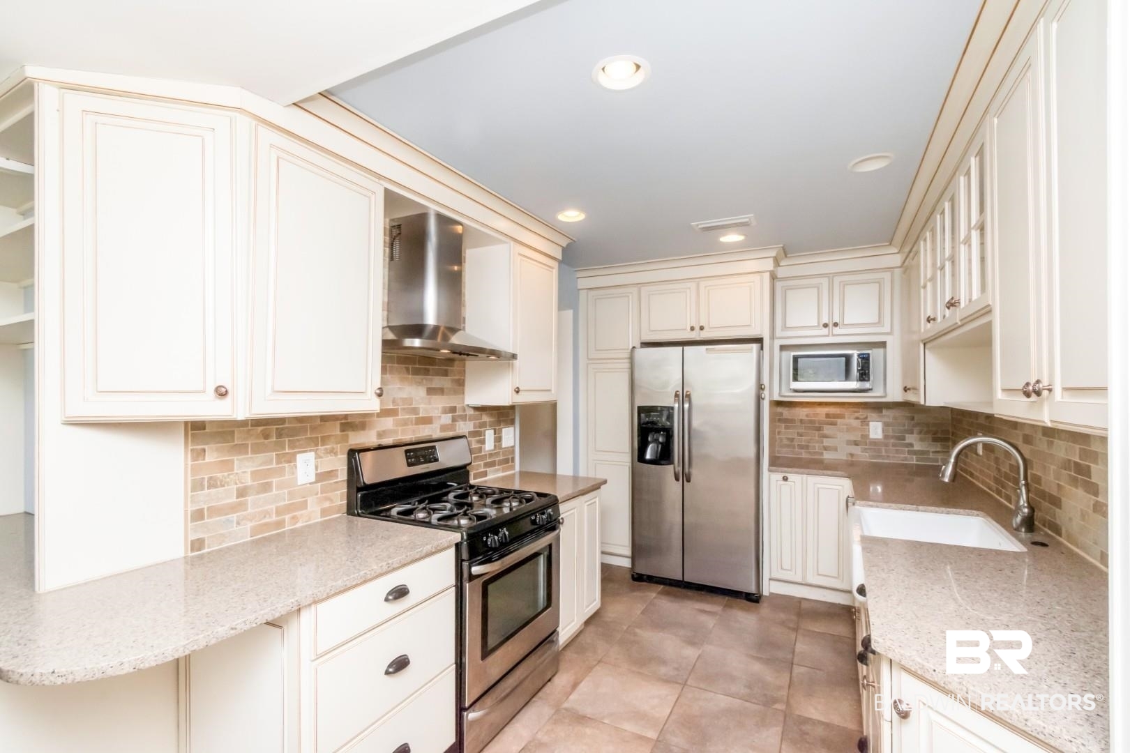 10 South Hathaway Road Mobile, AL 36608 - Photo 9 of 46 Kitchen with stainless steel appliances, wall chimney exhaust hood, light stone counters, light tile patterned flooring, and recessed lighting