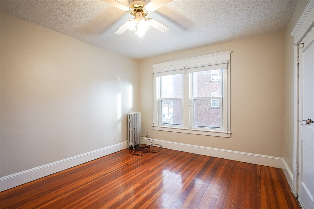 42 Montgomery Street, Unit 42 Westfield, MA 01085 - Photo 12 of 14 an empty room with wooden floor chandelier fan and windows