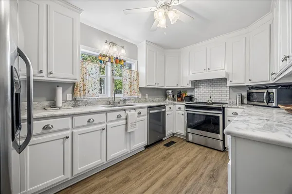 a kitchen with granite countertop white cabinets and white stainless steel appliances