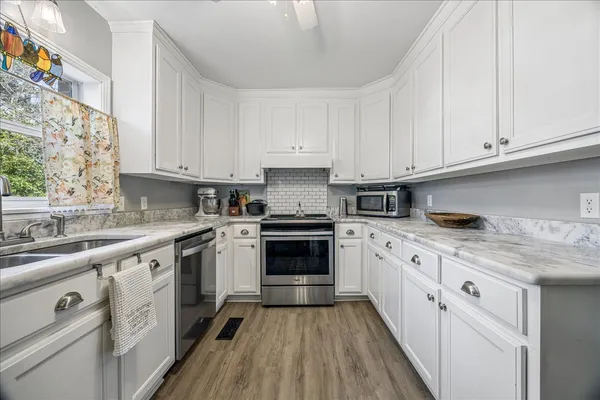 a kitchen with granite countertop white cabinets and white appliances