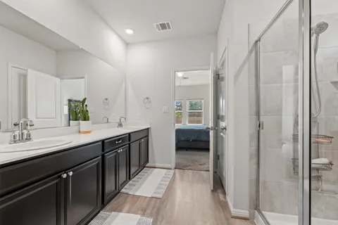 a en suite bathroom with a double vanity sink a mirror and a shower