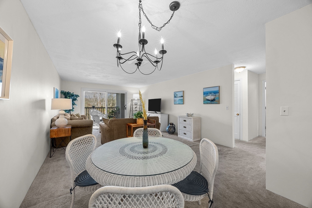 42 Old Colony Way, Unit 28 Orleans, MA 02653 - Photo 9 of 35 a living room with furniture a dining table and a chandelier