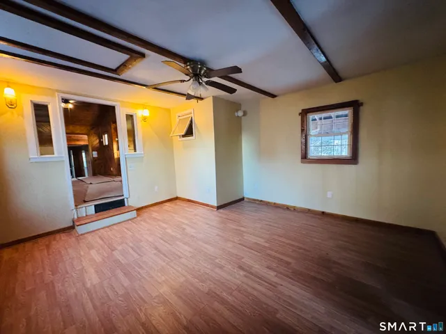 a view of a livingroom with wooden floor and a ceiling fan