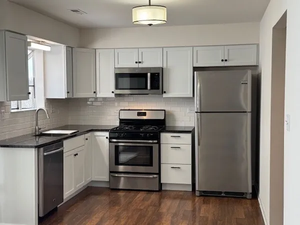 a kitchen with cabinets stainless steel appliances and wooden floor