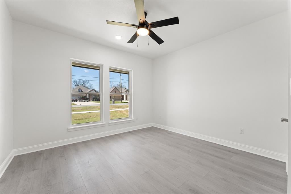 809 South Adelaide Street Terrell, TX 75160 - Photo 8 of 18 an empty room with wooden floor ceiling fan and windows